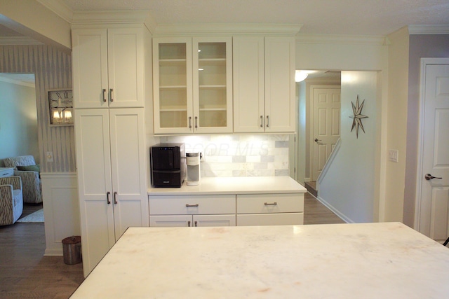 kitchen featuring crown molding, light countertops, dark wood-style flooring, and glass insert cabinets