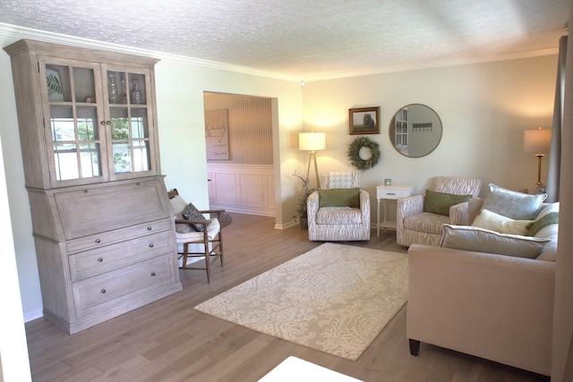 living area with a textured ceiling, ornamental molding, and wood finished floors
