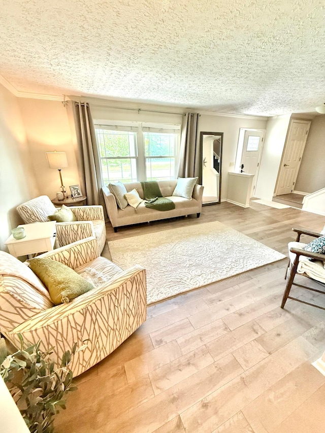 living room featuring baseboards, ornamental molding, a textured ceiling, and wood finished floors