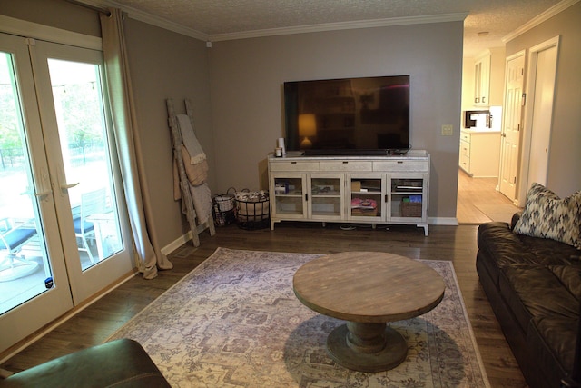 living room featuring crown molding, a textured ceiling, baseboards, and wood finished floors