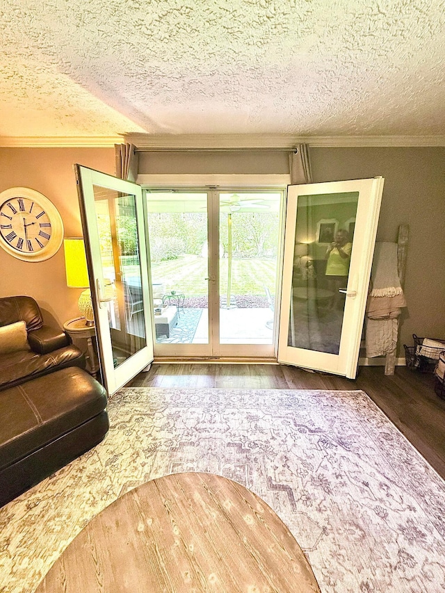 living room featuring french doors, ornamental molding, a textured ceiling, and wood finished floors