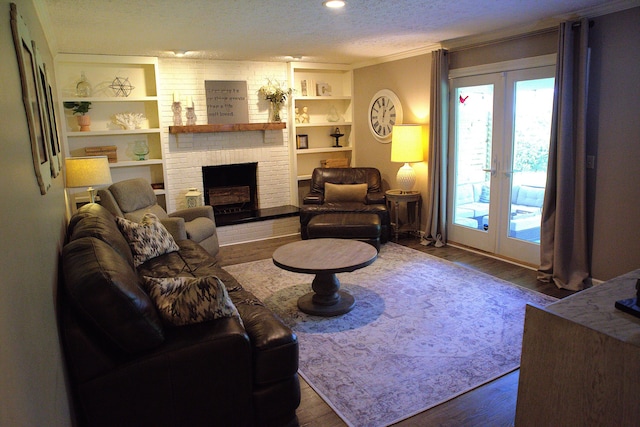 living area with french doors, a textured ceiling, a brick fireplace, and wood finished floors