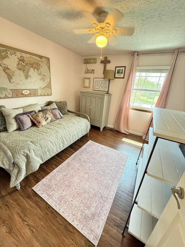 bedroom featuring baseboards, a textured ceiling, ceiling fan, and wood finished floors