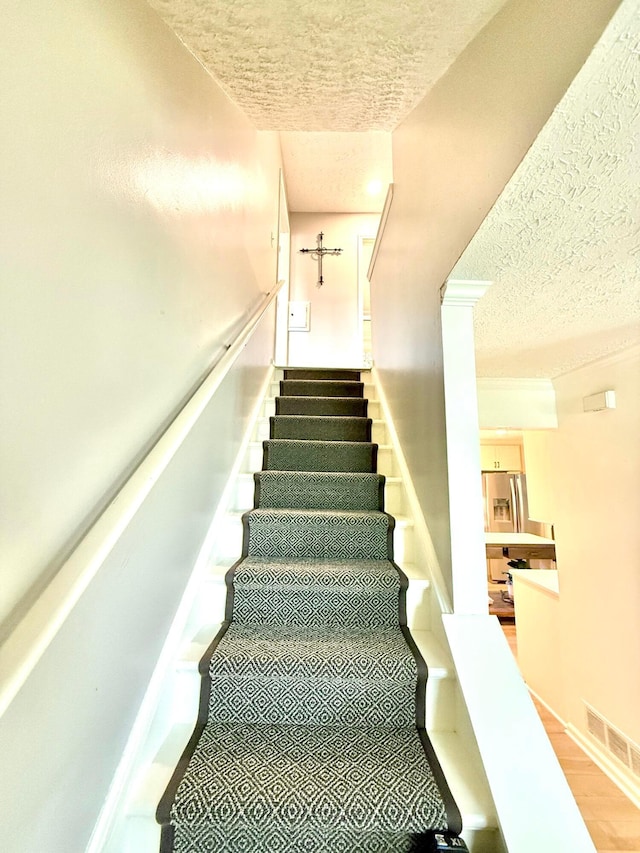 stairs featuring visible vents and a textured ceiling