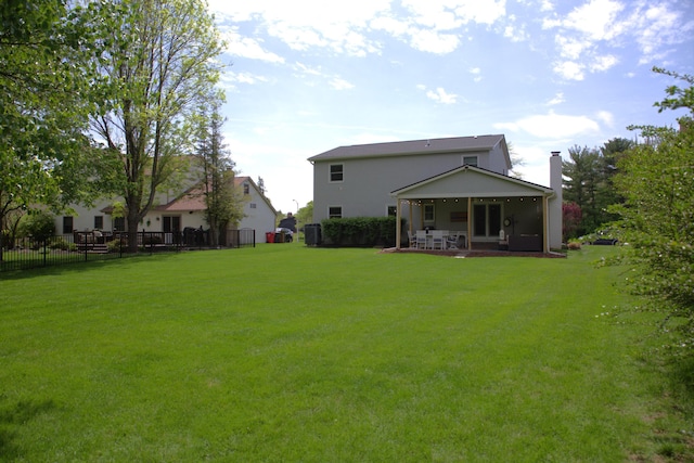 back of property with a lawn, fence, and a chimney