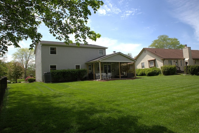 back of house featuring a lawn, fence, a sunroom, and stucco siding