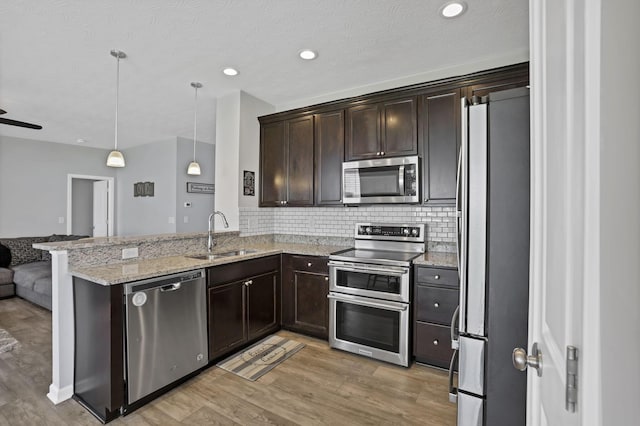 149 Broadmoore Blvd, Pataskala, OH 43062 - kitchen featuring dark brown cabinets, open floor plan, a sink, light wood finished floors, and stainless steel appliances