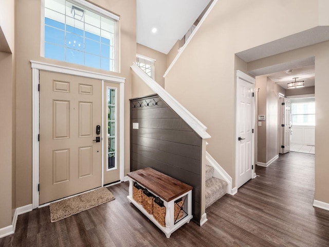 foyer featuring baseboards, wood finished floors, a wealth of natural light, and stairway