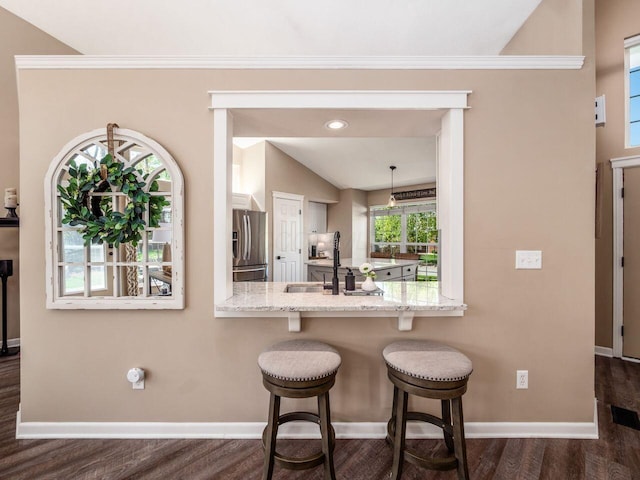 kitchen with lofted ceiling, baseboards, stainless steel refrigerator with ice dispenser, a sink, and dark wood finished floors