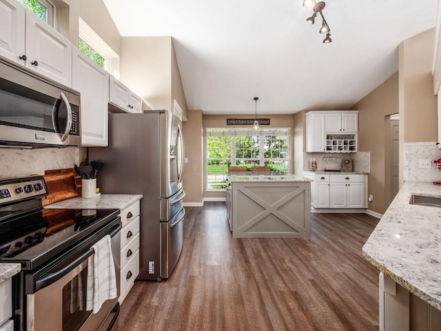 kitchen with dark wood-type flooring, appliances with stainless steel finishes, backsplash, and white cabinets