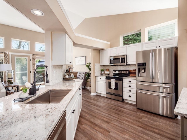 kitchen with decorative backsplash, appliances with stainless steel finishes, light stone countertops, a sink, and white cabinets