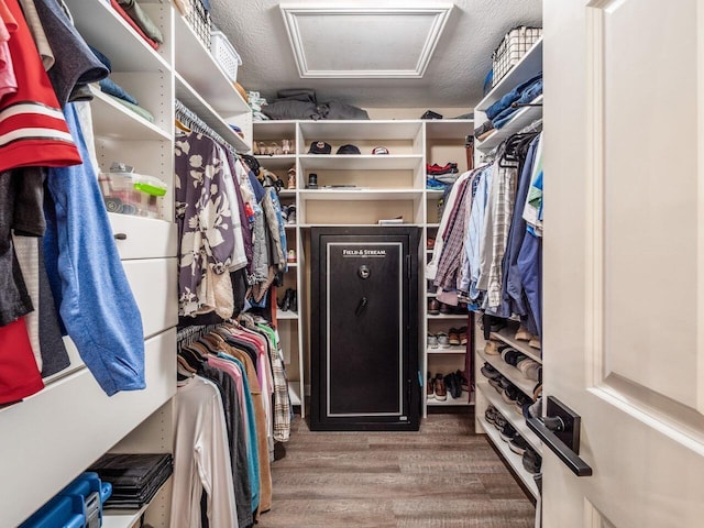 walk in closet with attic access and wood finished floors