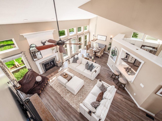 living area with a fireplace with flush hearth, wood finished floors, a wealth of natural light, and high vaulted ceiling