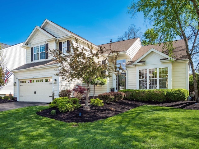 view of front of property with roof with shingles, an attached garage, a front lawn, and aphalt driveway