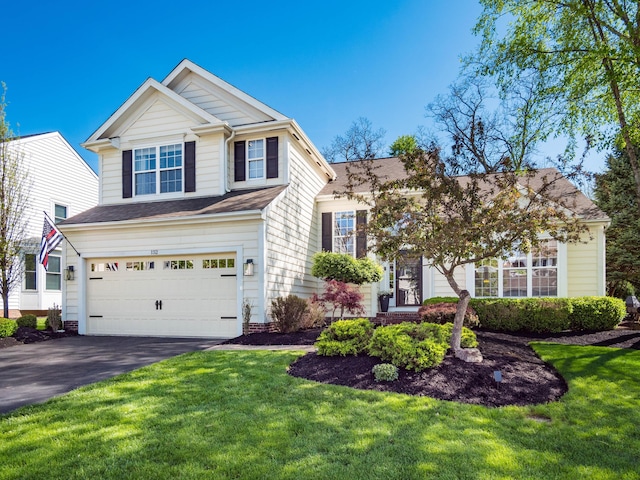 traditional home featuring roof with shingles, driveway, a front yard, and a garage