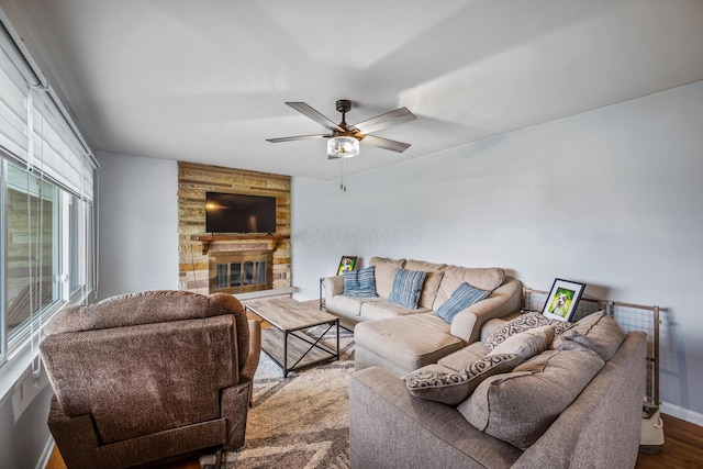 living room featuring baseboards, a fireplace, a ceiling fan, and wood finished floors