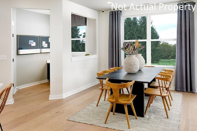 dining space with baseboards and light wood-style flooring