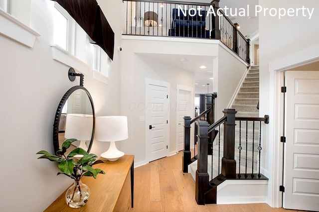 foyer entrance featuring wood finished floors, stairway, and a towering ceiling