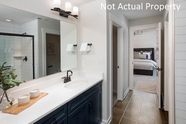 ensuite bathroom featuring tile patterned flooring, vanity, a textured ceiling, ensuite bathroom, and a stall shower