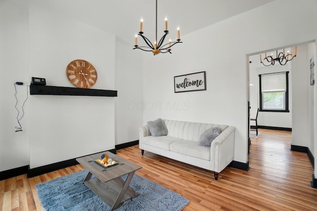living room with baseboards, an inviting chandelier, and wood finished floors