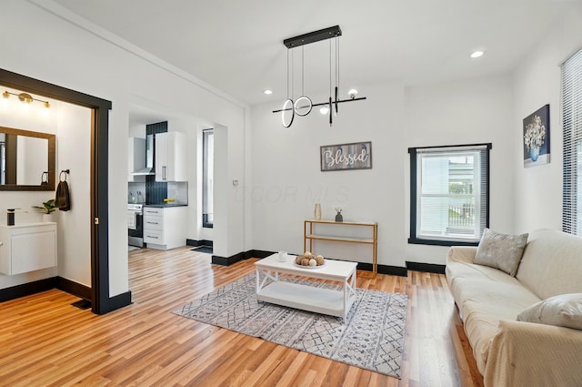living area featuring baseboards, light wood-type flooring, and a notable chandelier