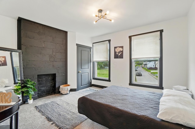 bedroom with carpet floors, a notable chandelier, and a fireplace