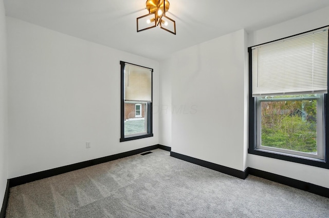 carpeted spare room featuring baseboards and visible vents