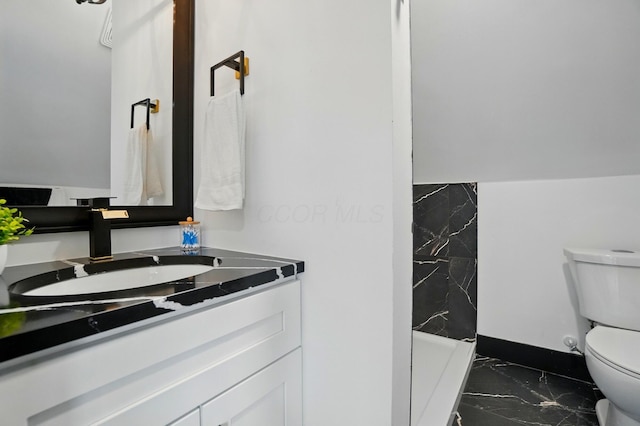 bathroom with toilet, marble finish floor, and vanity