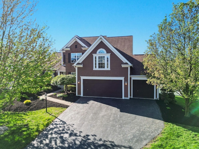 view of front of house featuring a garage, aphalt driveway, and a shingled roof
