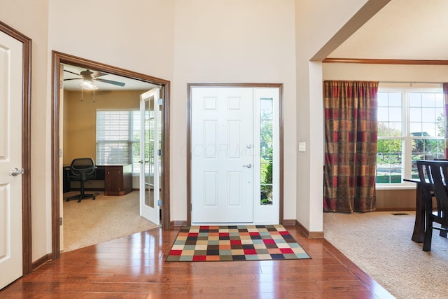 carpeted foyer with a ceiling fan, a healthy amount of sunlight, and hardwood / wood-style floors