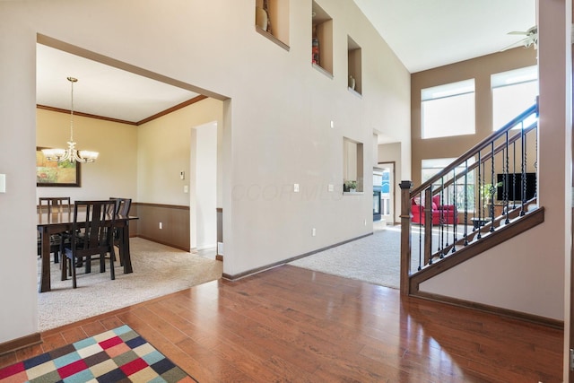 entrance foyer featuring a towering ceiling, hardwood / wood-style flooring, stairway, baseboards, and a notable chandelier
