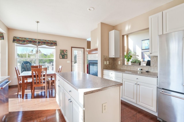 kitchen with light countertops, dark wood finished floors, stainless steel appliances, tasteful backsplash, and a kitchen island