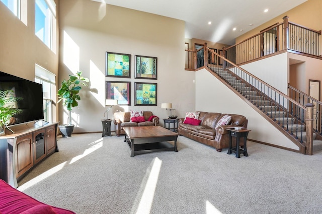 living area with carpet floors, a high ceiling, and stairs
