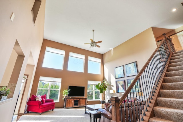 carpeted living room with a healthy amount of sunlight, a high ceiling, and stairs