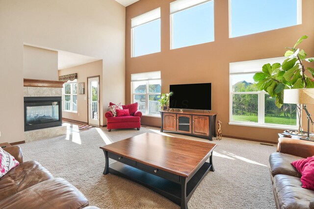 carpeted living room featuring a healthy amount of sunlight, a high ceiling, a fireplace, and visible vents