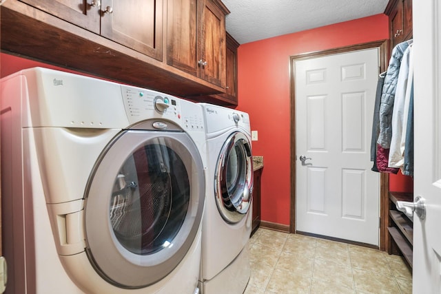 clothes washing area featuring a textured ceiling, washing machine and dryer, cabinet space, light tile patterned floors, and baseboards