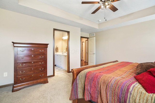 bedroom featuring visible vents, a sink, baseboards, ensuite bathroom, and light carpet