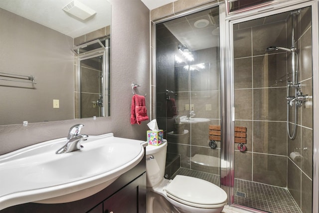 bathroom with toilet, a textured wall, a shower stall, and vanity