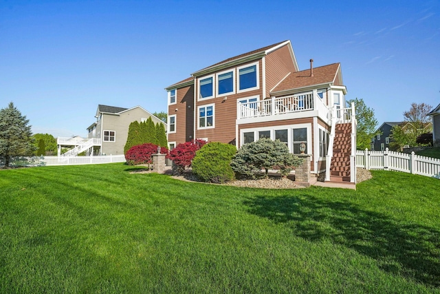 rear view of house with a lawn, fence, a balcony, and stairway