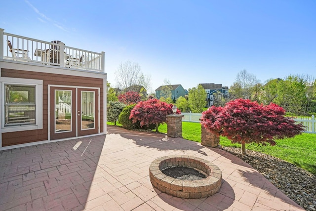 view of patio with fence, an outdoor fire pit, and a balcony