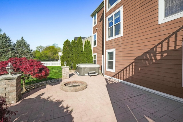 view of patio featuring a hot tub, fence, and an outdoor fire pit