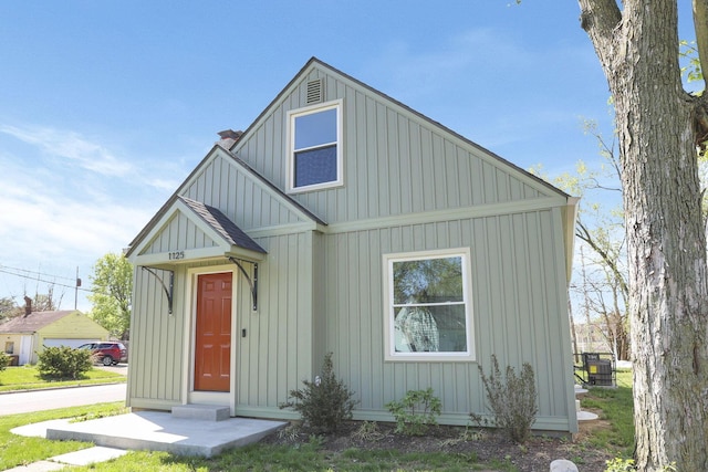 bungalow featuring board and batten siding and a chimney