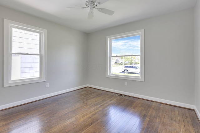 unfurnished room with dark wood-style flooring, baseboards, visible vents, and ceiling fan