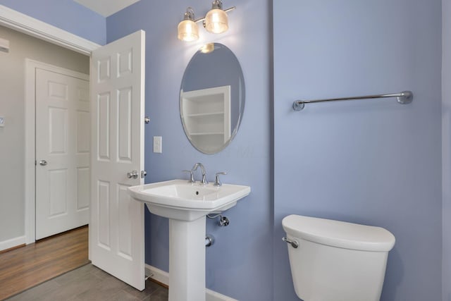 bathroom featuring baseboards, a sink, and toilet