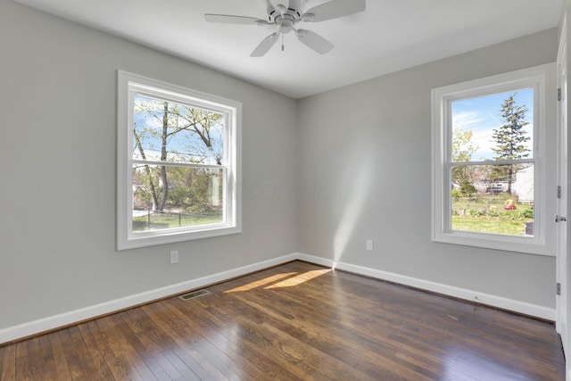 empty room with dark wood-style flooring, baseboards, and a healthy amount of sunlight