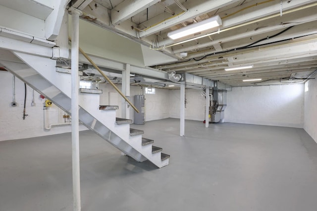 unfinished basement featuring stairs and water heater