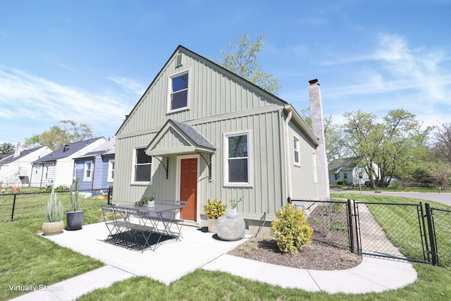 view of front of house featuring fence, a front yard, a chimney, a gate, and board and batten siding