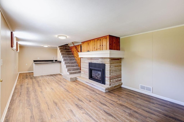 unfurnished living room with crown molding, baseboards, visible vents, and wood finished floors