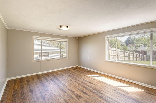 unfurnished room with baseboards, ornamental molding, and wood finished floors
