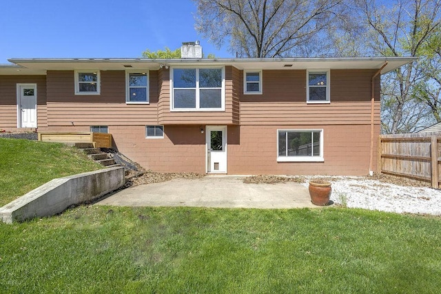 back of property with a lawn, a patio, fence, and a chimney
